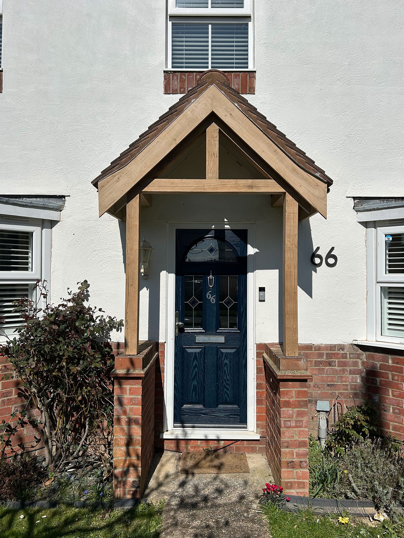 Oak-framed porch with a gabled tiled roof on brick plinths over a front door