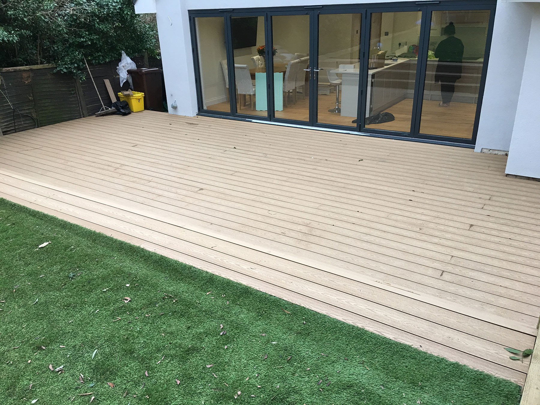 Composite decking laid level with bifold doors, leading out onto the lawn