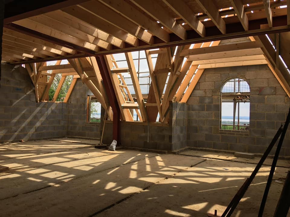 Loft conversion in progress with new rafters, rooflights and an arched gable window